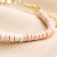 Close up of Pink and White Semi-Precious Heishi Beaded Bracelet on neutral coloured material