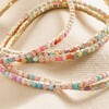 Close up of crystals on Set of 5 Multicoloured Crystal Tennis Bracelets in Gold against beige fabric