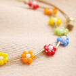 Close up of beads on Colourful Daisy Beaded Cord Bracelet against beige fabric