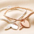 Personalised Beaded Wing Charm Bracelets in silver and rose gold on top of beige fabric