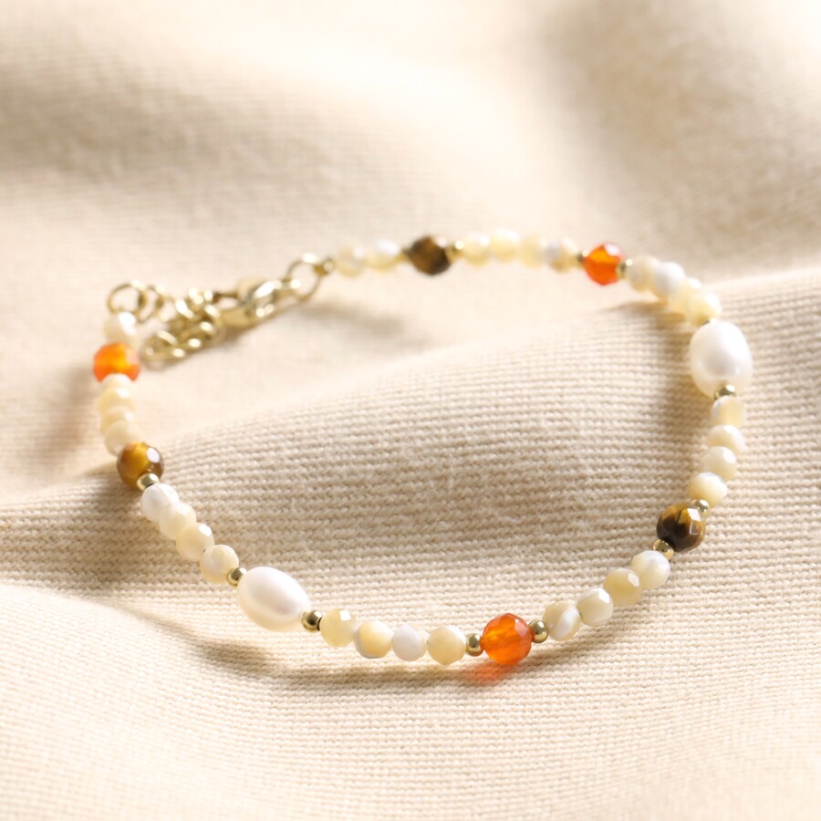 Natural Semi-Precious Stone and Pearl Beaded Bracelet on top of beige coloured material