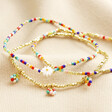 Set of 3 Rainbow and Gold Miyuki Daisy Beaded Bracelets on top of beige coloured fabric
