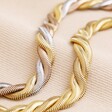 Gold Stainless Steel Chunky Triple Snake Chain Bracelet with mixed metal version against beige coloured material