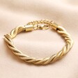 Gold Stainless Steel Chunky Triple Snake Chain Bracelet on top of beige coloured material