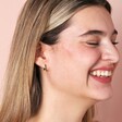 Green Baguette Crystal Huggie Hoop Earrings in Silver on model smiling against beige backdrop
