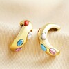 Gold Stainless Steel Multicoloured Oval Stone Half Hoop Earrings on top of beige coloured material