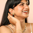 Oversized Sea Flower Stud Earrings in Gold on model smiling against pink backdrop