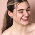 Oversized Sea Flower Stud Earrings in Gold on model smiling against pink backdrop
