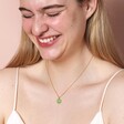 Green Enamel Organic Leaf Pendant Necklace in Gold on model smiling against beige background
