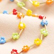 Close Up of Multicoloured Daisy Beaded Necklace in Gold on Pink FabricMulticoloured Daisy Beaded Necklace in Gold