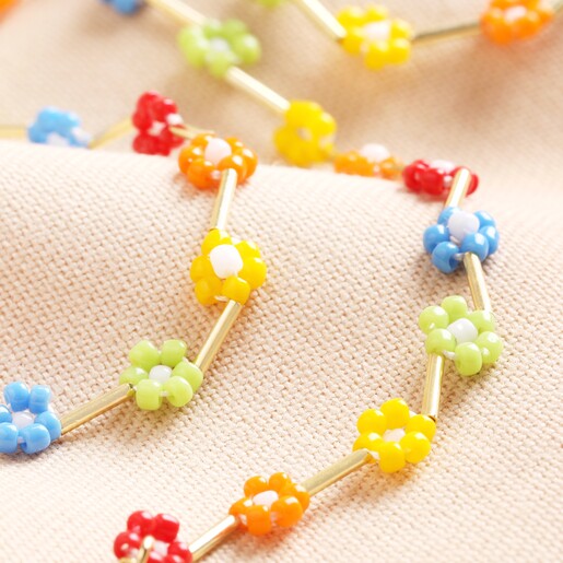 Close Up of Multicoloured Daisy Beaded Necklace in Gold on Pink FabricMulticoloured Daisy Beaded Necklace in Gold