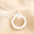 Organic Infinity Knot Necklace in Silver against beige coloured fabric 
