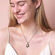 Model smiling wearing Personalised Photo Antiqued Crystal Star Oval Locket Necklace in front of beige background