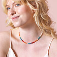 Model smiling wearing Rainbow Rondelle Stone Beaded Necklace against beige coloured background