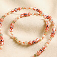 Red Stone Multicoloured Beaded Necklace laid on top of beige coloured fabric