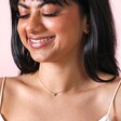Gold Stainless Steel Tiny Round Heart Charm Necklace on model smiling against neutral backdrop