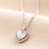 Close up of Stainless Steel Tiny Antiqued Heart Pendant Necklace on Beige Background