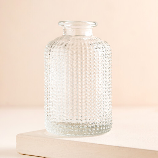 Empty Clear Glass Dimpled Bottle Vase on a Beige Background