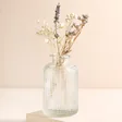 Clear Glass Dimpled Bottle Vase with Dried Posy on a Beige Background