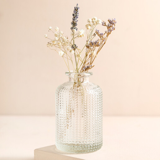 Clear Glass Dimpled Bottle Vase with Dried Posy on a Beige Background