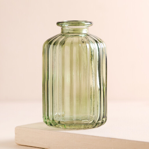 Empty Green Glass Ribbed Bottle Vase on a Beige Background