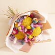 Luxury Rainbow Brights Dried Flower Bouquet laid on top of beige coloured background