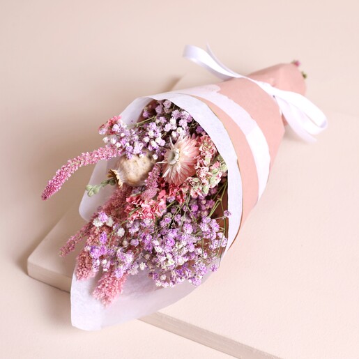 Summer Loving Dried Flower Posy in paper on top of neutral backdrop
