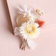 Nancy Dried Flower Wedding Buttonhole laid on top of raised beige surface