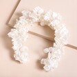 White Hydrangea Dried Flower Wedding Headband against raised beige backdrop