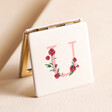 U Floral Initial Compact Mirror standing on top of beige coloured backdrop