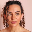Chunky Twisted Rope Half Hoop Earrings in Silver on Model in front of pink backdrop