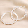 Triple Layered Thread Hoop Earrings in Silver on top of neutral coloured material