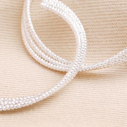 Close up of Triple Layered Thread Hoop Earrings in Silver on top of beige fabric