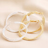 Triple Layered Thread Hoop Earrings in Gold with silver version on top of beige material