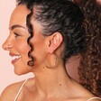 Model smiling against pink backdrop wearing Triple Layered Thread Hoop Earrings in Gold