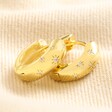 Crystal Stars Huggie Hoop Earrings in Gold on Beige Fabric