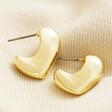 Molten Heart Half Hoop Earrings in Gold on top of beige coloured fabric