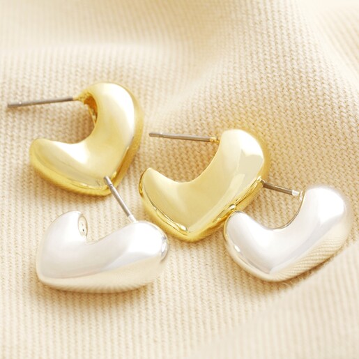 Molten Heart Half Hoop Earrings in Gold with silver version on top of neutral coloured material