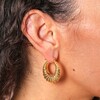 Close up of Twisted Rope Creole Hoop Earrings in Gold on model