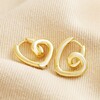 Small Scribble Heart Hoop Earrings in Gold on top of beige coloured fabric