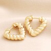 Twisted Rope Creole Heart Hoop Earrings In Gold on beige Fabric