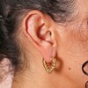 Close Up of Twisted Rope Creole Heart Hoop Earrings In Gold on Model