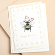 This card eatures an embossed design of a delicate bee holding a sprig of flowers highlighted by a shimmering gold foil outline