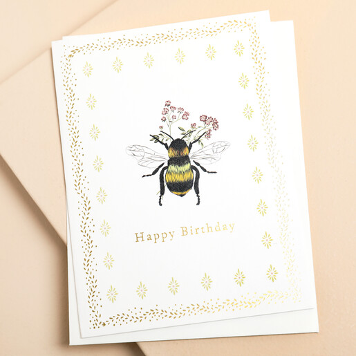 This card eatures an embossed design of a delicate bee holding a sprig of flowers highlighted by a shimmering gold foil outline