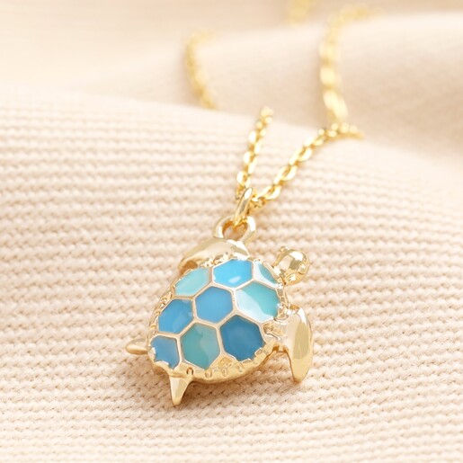 Close up Blue Turtle Pendant Necklace in Gold on a neutral background