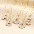 Bubble letter initial pendants in gold encrusted with cubic zirconas.