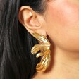 Big Metal London Floral Stainless Steel Earrings in Gold on a neutral cream background on a model