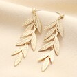 Big Metal London Long Leaf Dangle Earrings Gold  on a neutral cream background