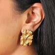 Close Up of Stainless Steel Molten Rectangular Stud Earrings in Gold on Model