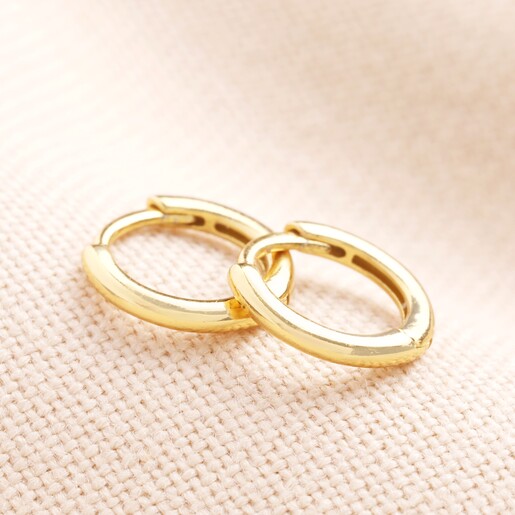 Tiny Gold Sterling Silver Slim Huggie Hoop Earrings against beige fabric
